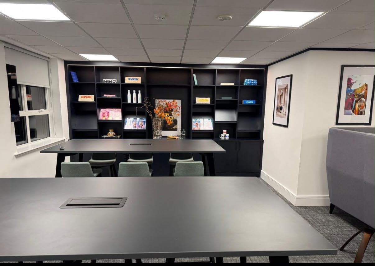 Commercial joinery in an office meeting room with full-height dark fitted shelving and cupboards