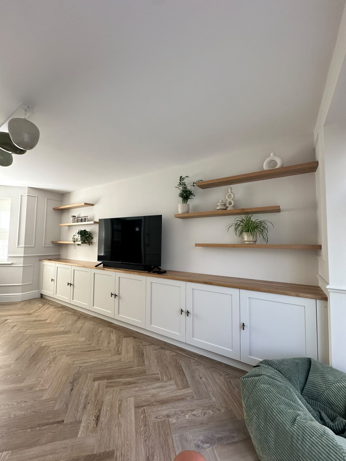 Full-width bespoke media wall with painted shaker cabinets, solid oak worktop and floating oak shelves